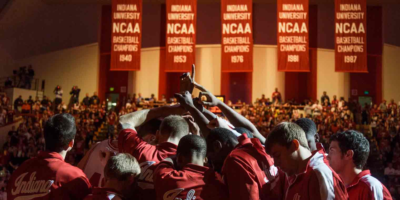 IU basketball team with five national championship banners in background