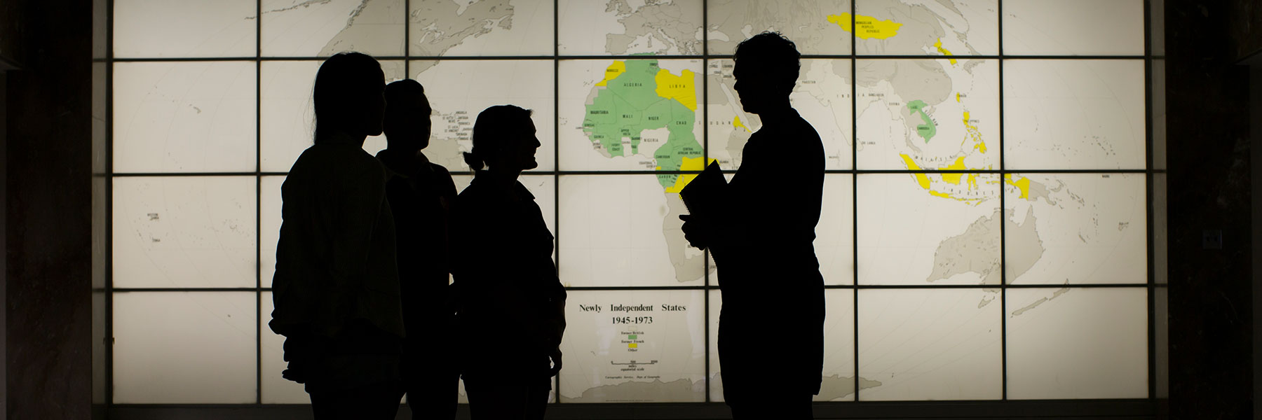 People silhouetted in front of a world map
