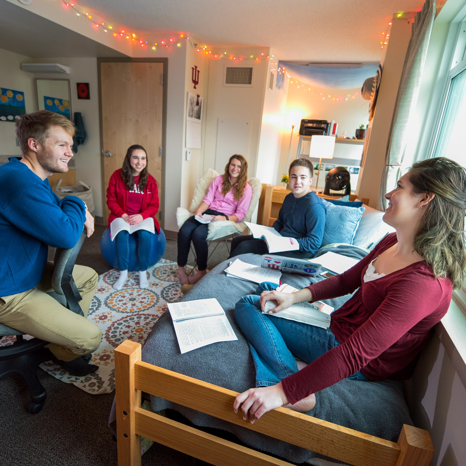 Students have a conversation in a dorm room.